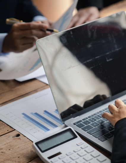 Two people sitting at desk discussing with a calculator